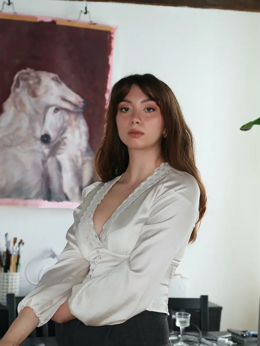 Elle Montrose in her Paris studio, standing in front of a large painting of borzois